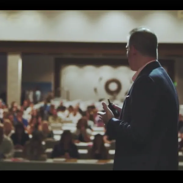 David Lee Jensen from behind, addressing a packed ballroom audience mid-keynote
